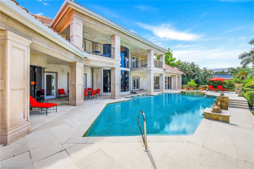Two-story home overlooking a pool, with columned balconies and a tiled patio.