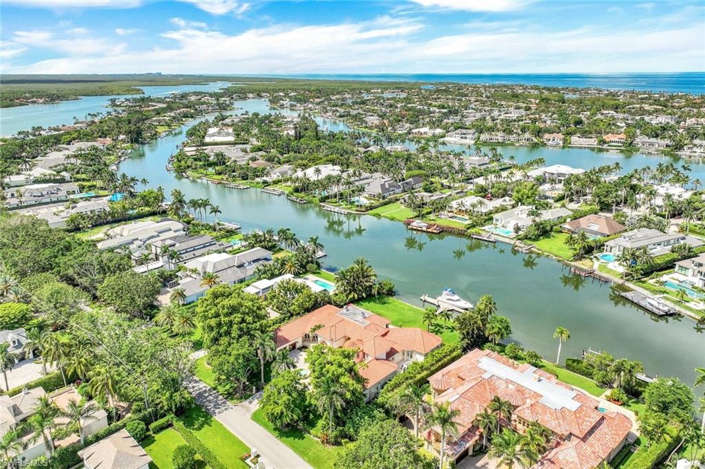 Aerial view of a Naples waterfront neighborhood with winding canals and palm-lined homes.