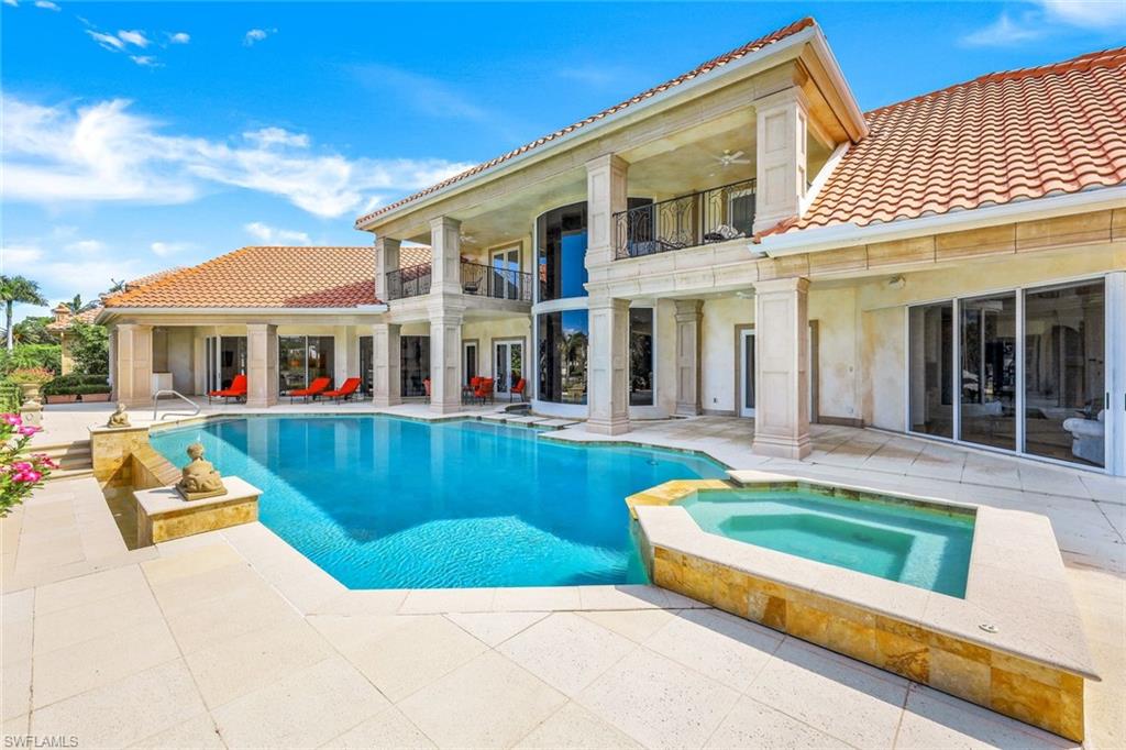 Two-story home with a columned balcony overlooking a swimming pool and raised spa.