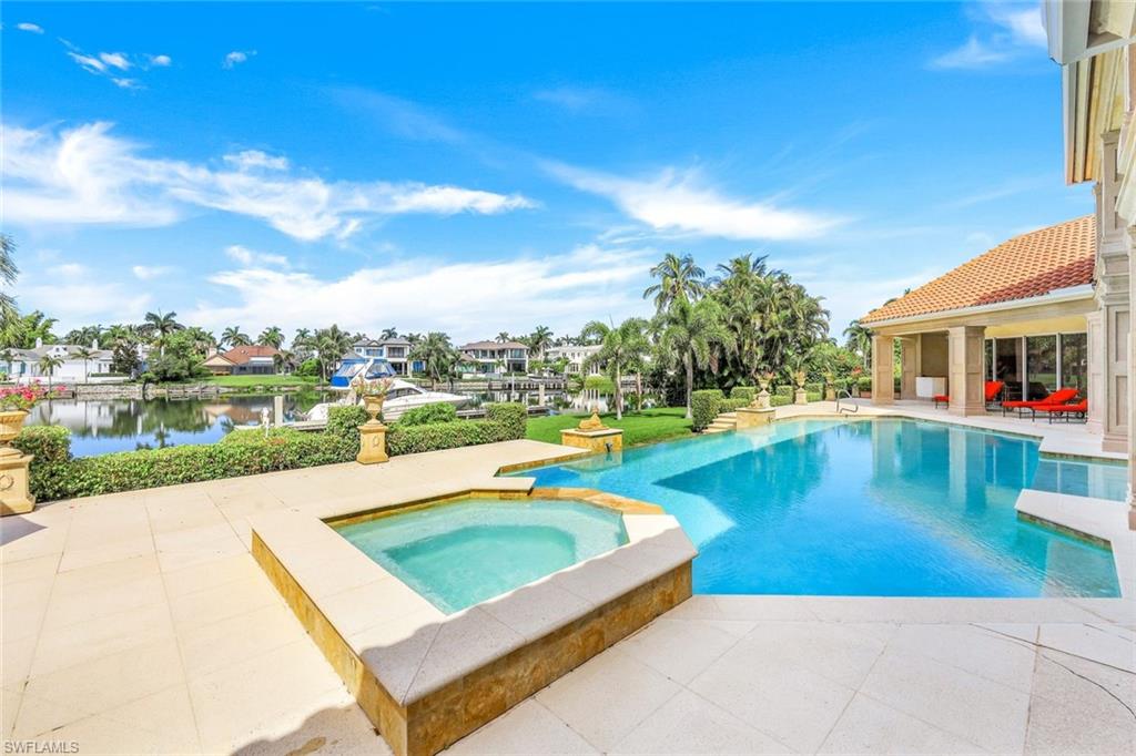 Backyard pool and raised spa overlook a landscaped canal beside a covered lanai.