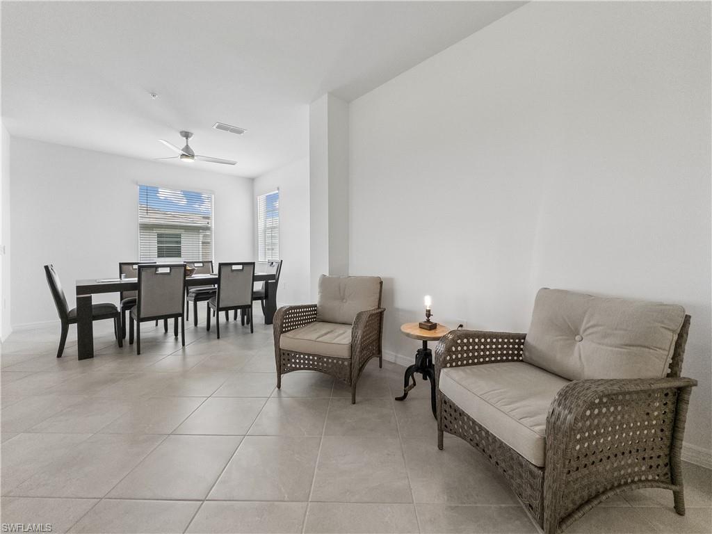 Open living and dining area with wicker seating, tiled floors, and a dark dining table.