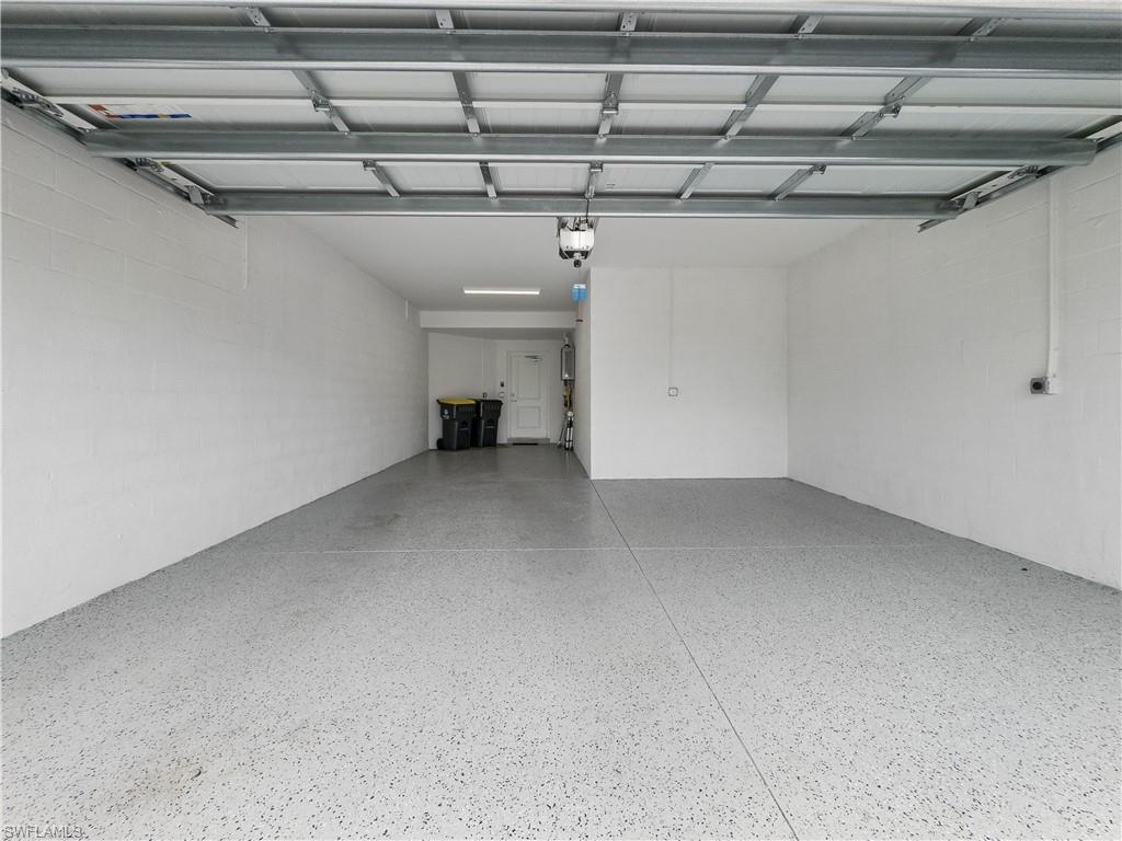 Empty garage with a speckled epoxy floor and open overhead door.