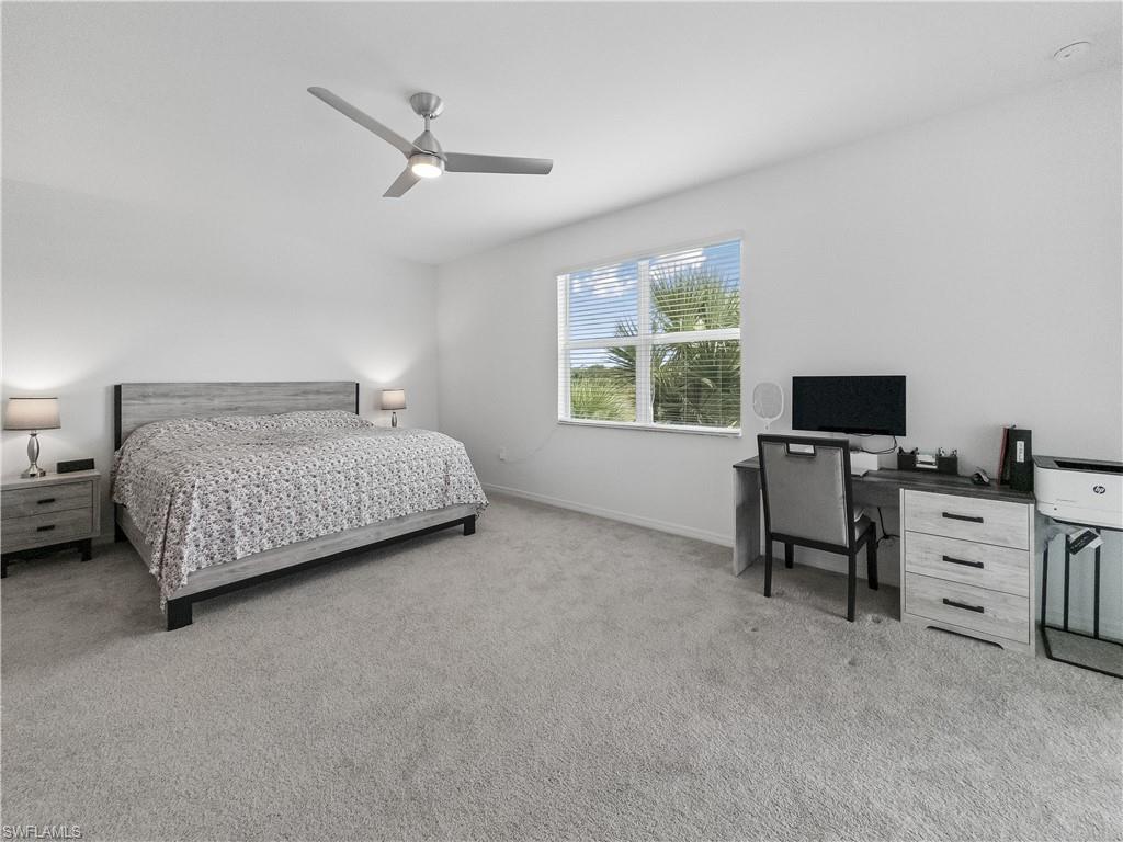 Furnished bedroom with a king-size bed, desk, and window overlooking palm trees.