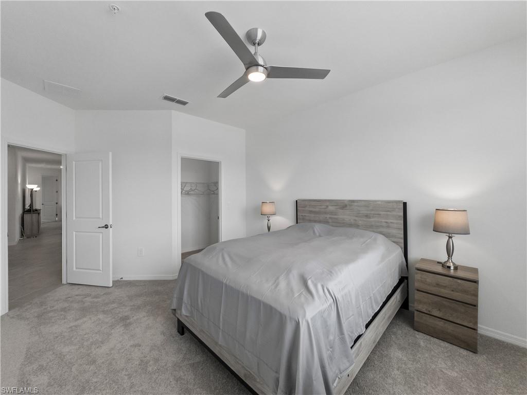 Bedroom with a king-size bed, gray wood headboard, ceiling fan, and open closet.