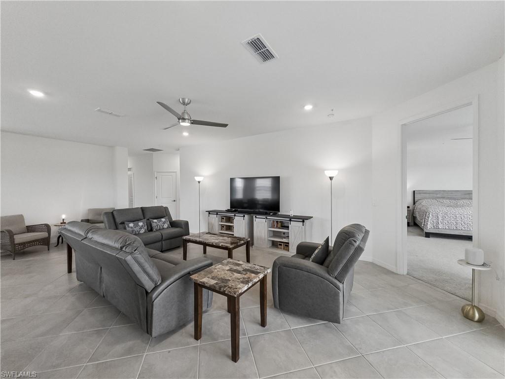 Furnished living room with gray seating, a television, and a view into the bedroom.
