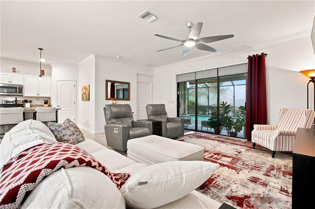 Furnished living room with gray recliners and sliding doors overlooking a screened pool lanai.