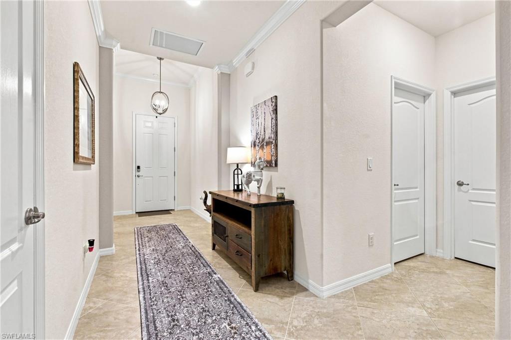 Foyer with tiled floors, a patterned runner, dark wood console table, and hanging globe pendant.