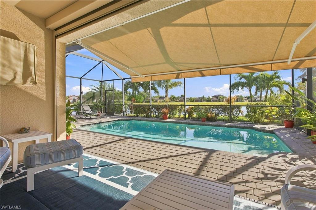 Screened pool lanai with a retractable shade canopy and palm-lined view.