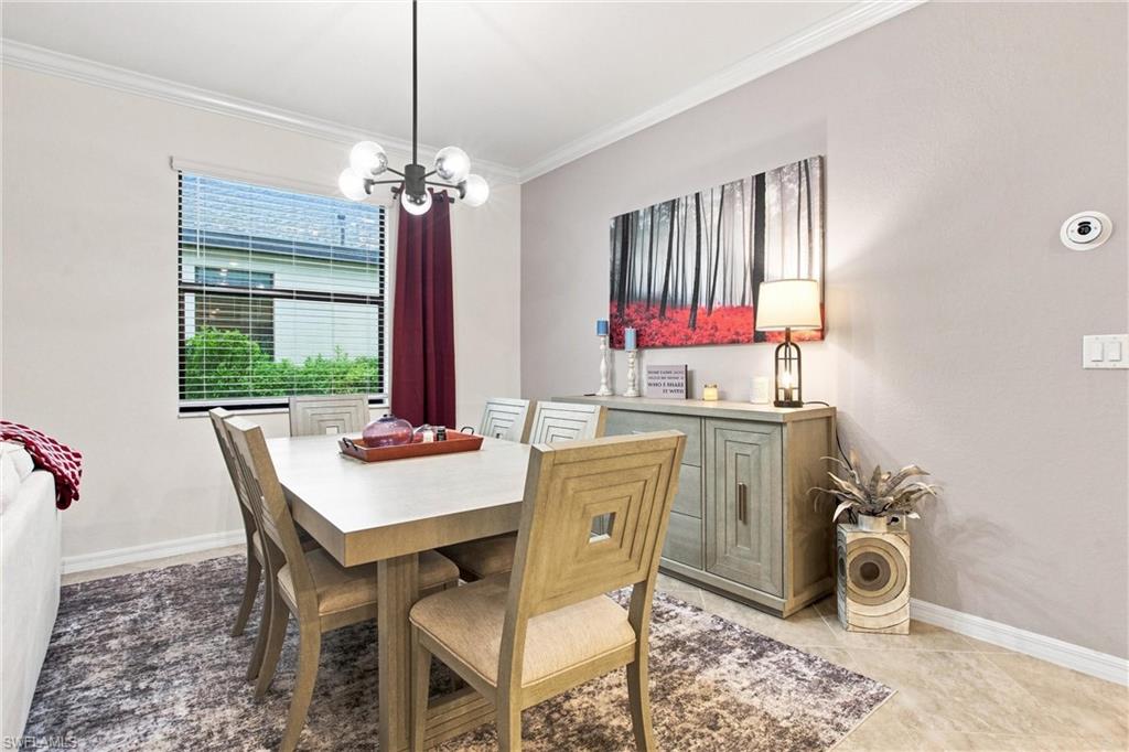 Dining room with a rectangular table, patterned rug, and sideboard beneath forest artwork.