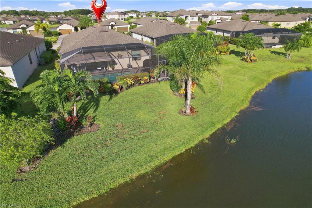Aerial view of a home with a screened lanai and landscaped waterfront lawn.
