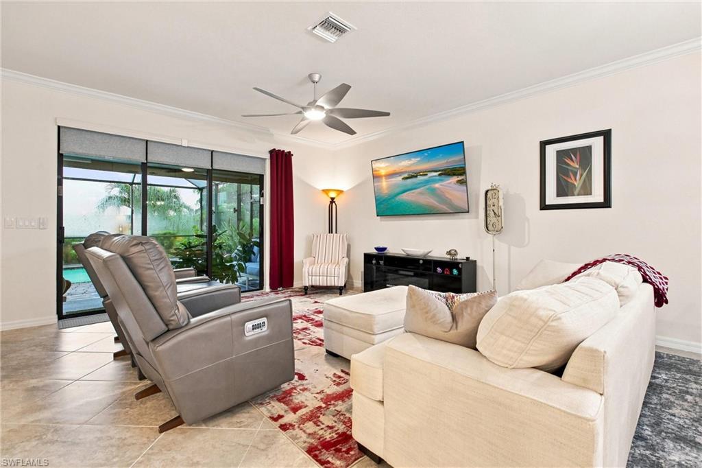 Furnished living room with a white sectional and gray recliner facing sliding doors to a pool lanai.