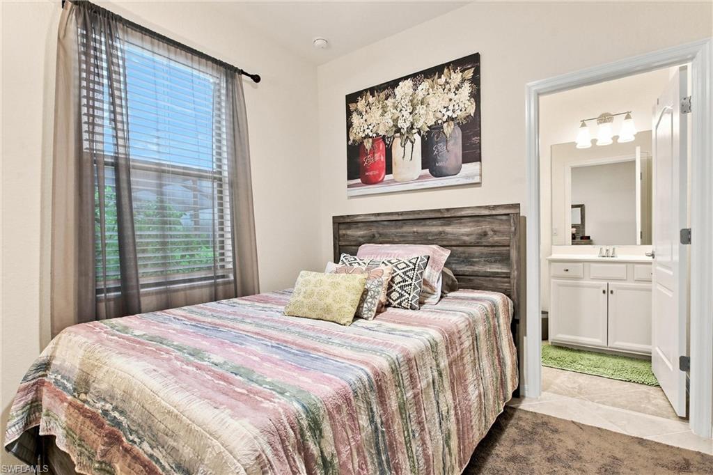 Furnished bedroom with a striped bedspread, dark wood headboard, and open doorway to a bathroom.