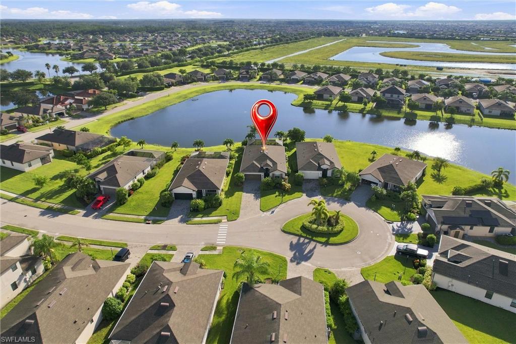 Aerial view of the marked home beside a large pond in a residential neighborhood.