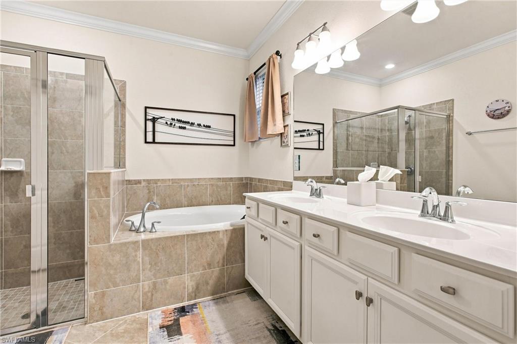 Bathroom with a corner soaking tub, glass shower, and long double-sink vanity.