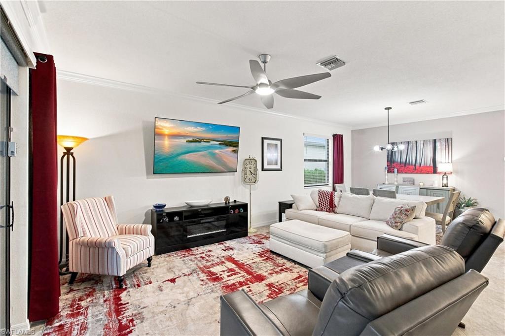 Living room with a white sectional, gray leather seating, patterned rug, and open dining area.