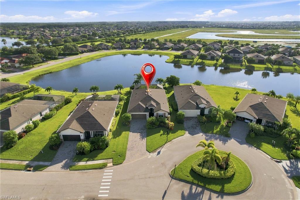 Aerial view of the marked home beside a pond and landscaped cul-de-sac.