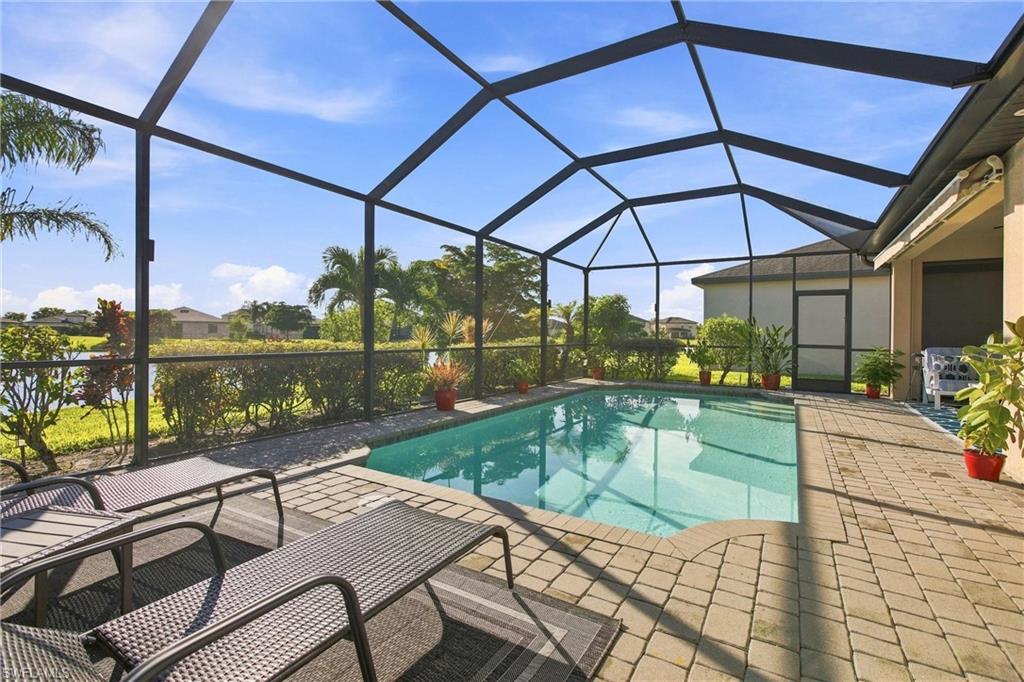 Swimming pool in a screened lanai with paver deck and lounge chairs.