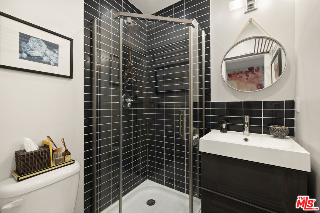 Bathroom with a glass-enclosed shower, black tile, and a dark floating vanity.