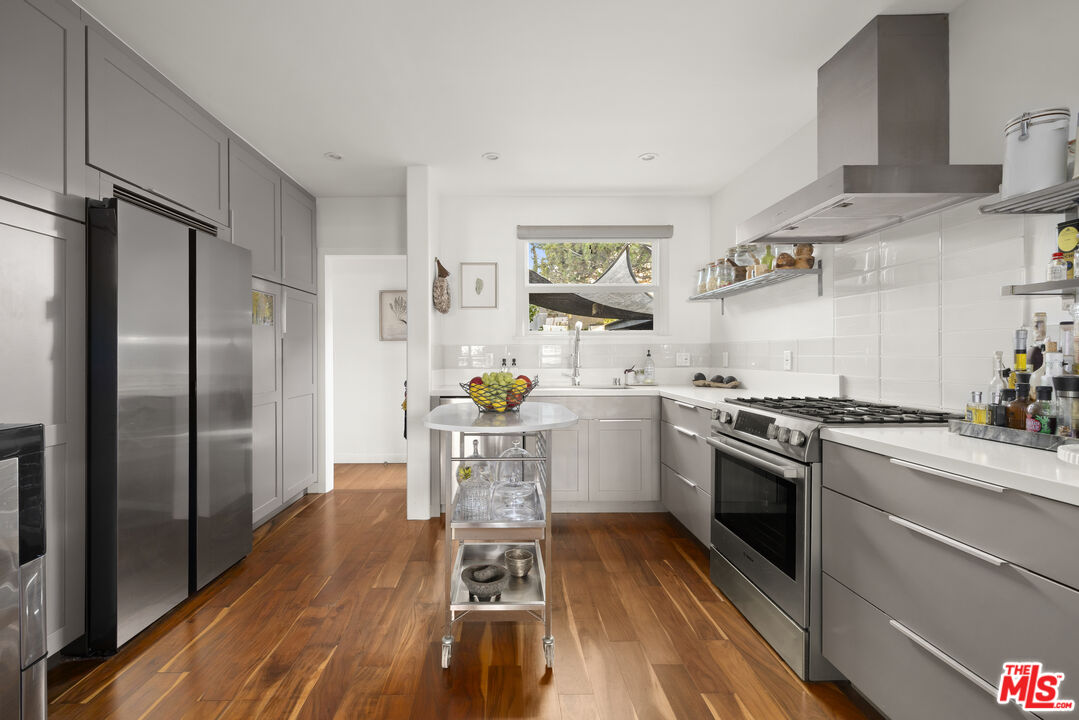 Modern kitchen with gray cabinetry, stainless steel appliances, and a central island cart.