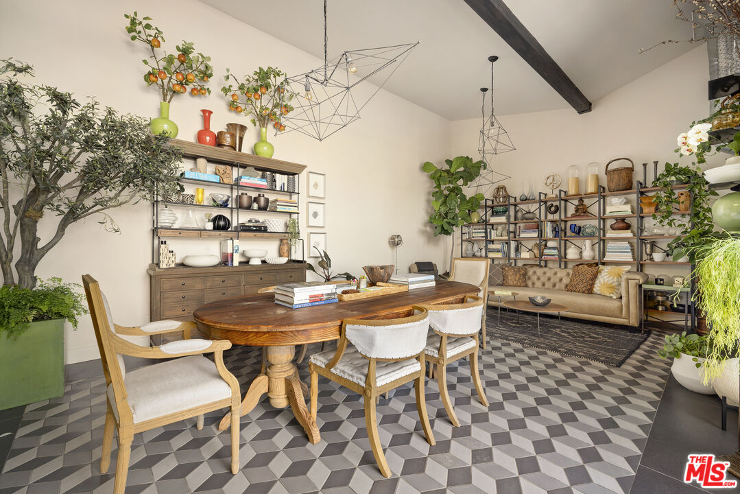 Dining area with a sculptural wood table, patterned tile floor, and adjoining sofa seating.
