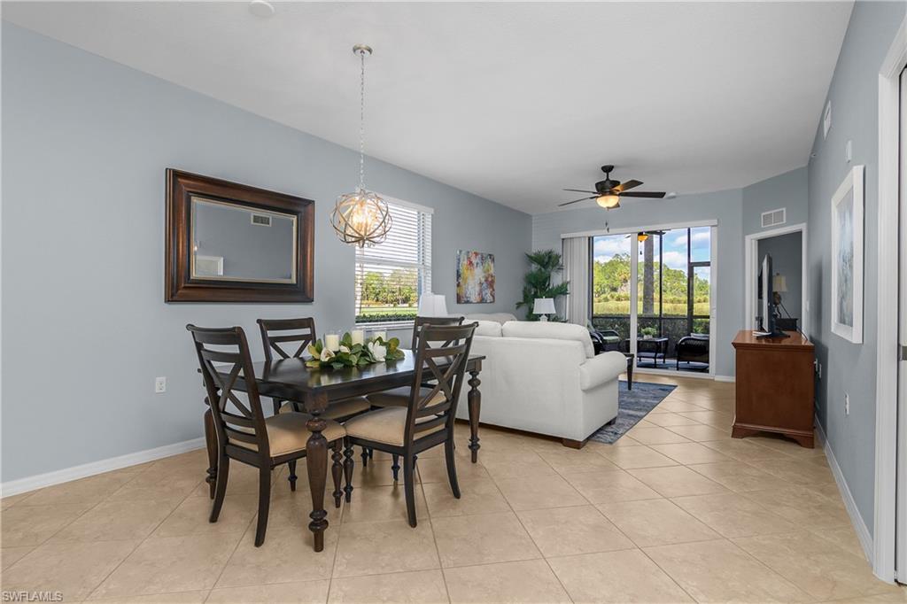 Open-plan living and dining room with a white sofa, dark wood table, and screened lanai views.