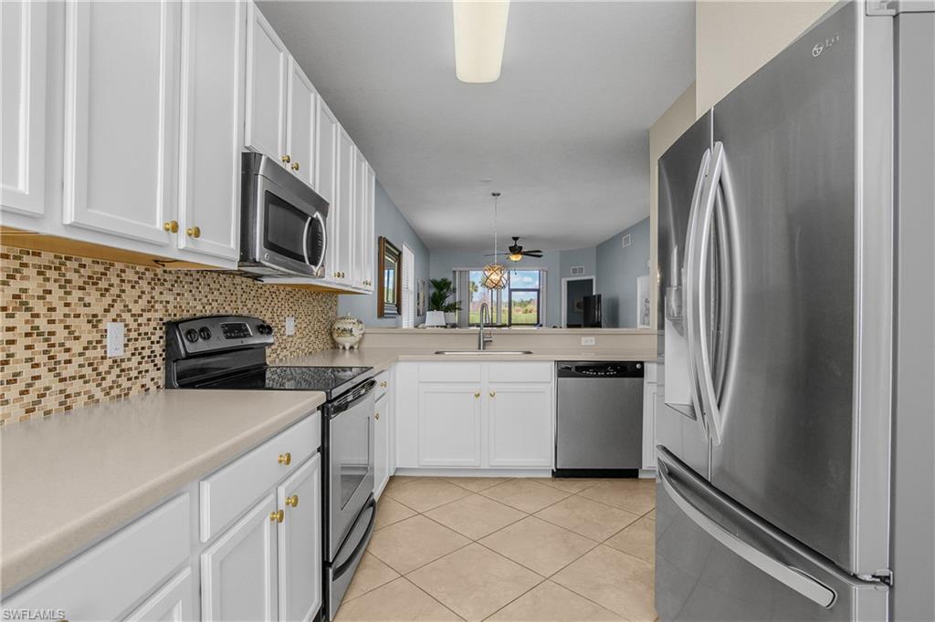 Kitchen with white cabinets, stainless steel appliances, and a peninsula sink opening to the living area.