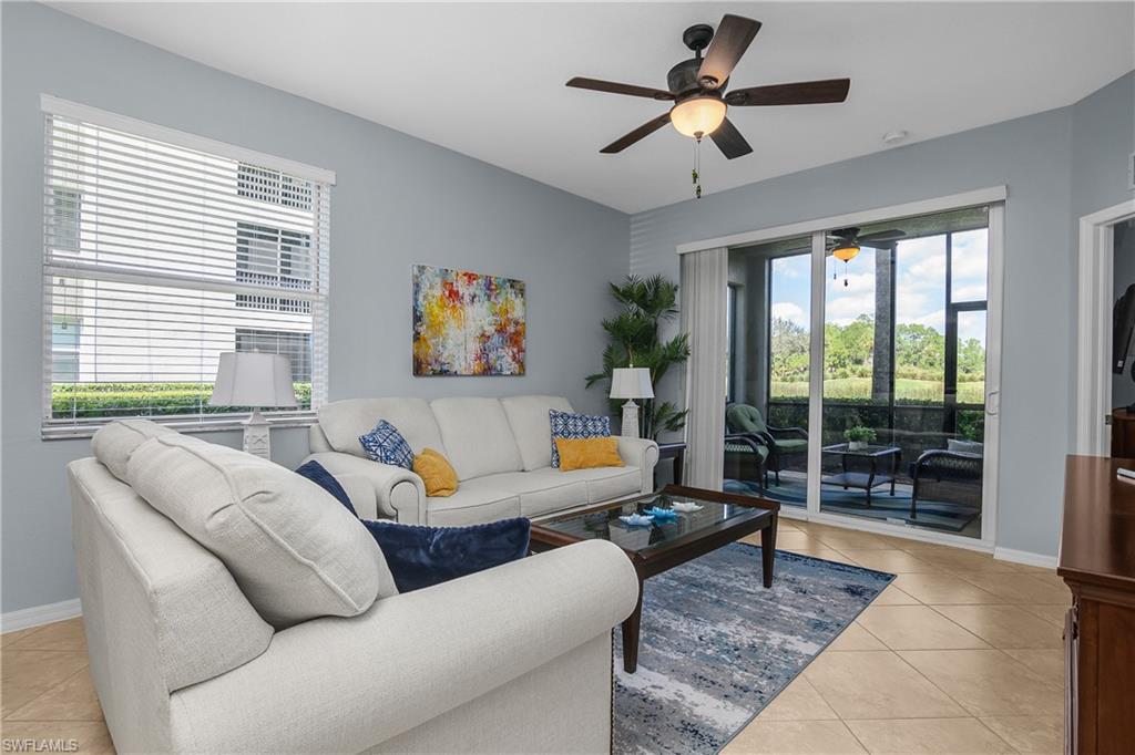 Living room with white sofas and a screened lanai visible through sliding glass doors.