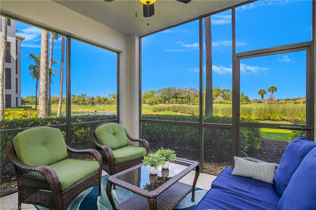 Screened lanai with wicker seating and a blue sofa overlooking a pond.