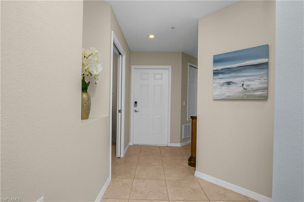 Entry hallway with a white front door, tiled floor, orchid niche, and coastal artwork.
