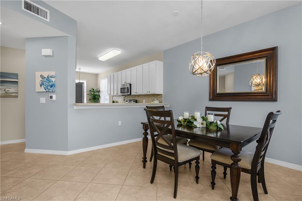 Dining area with dark wood table, decorative pendant light, and open kitchen with white cabinets.