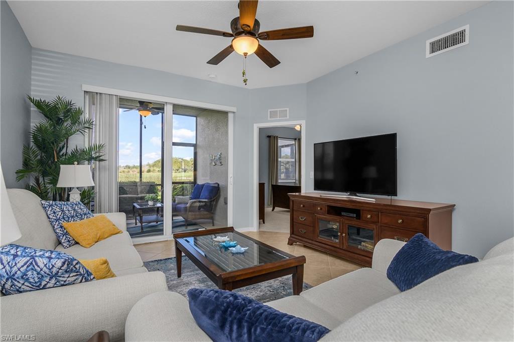 Living room with light sofas, blue and yellow pillows, and sliding doors to a patio.