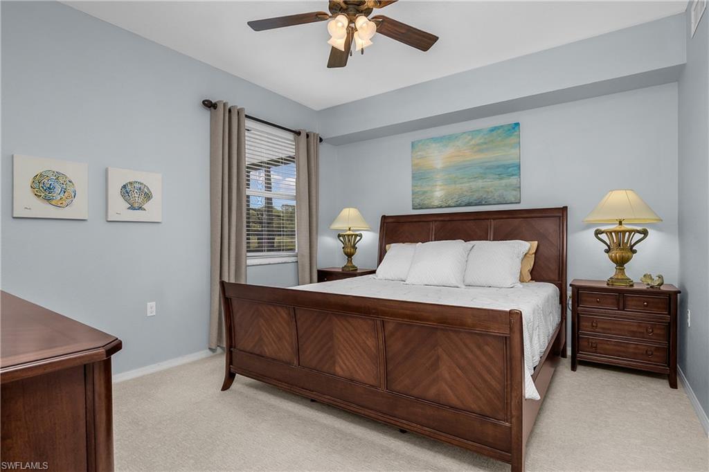 Bedroom with a dark wood bed, white bedding, matching lamps, and beach-themed artwork.