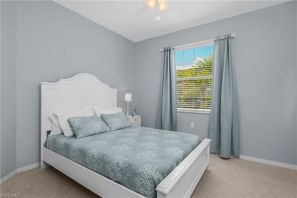 Bedroom with a white bed, pale blue patterned bedding, and a window framed by gray curtains.
