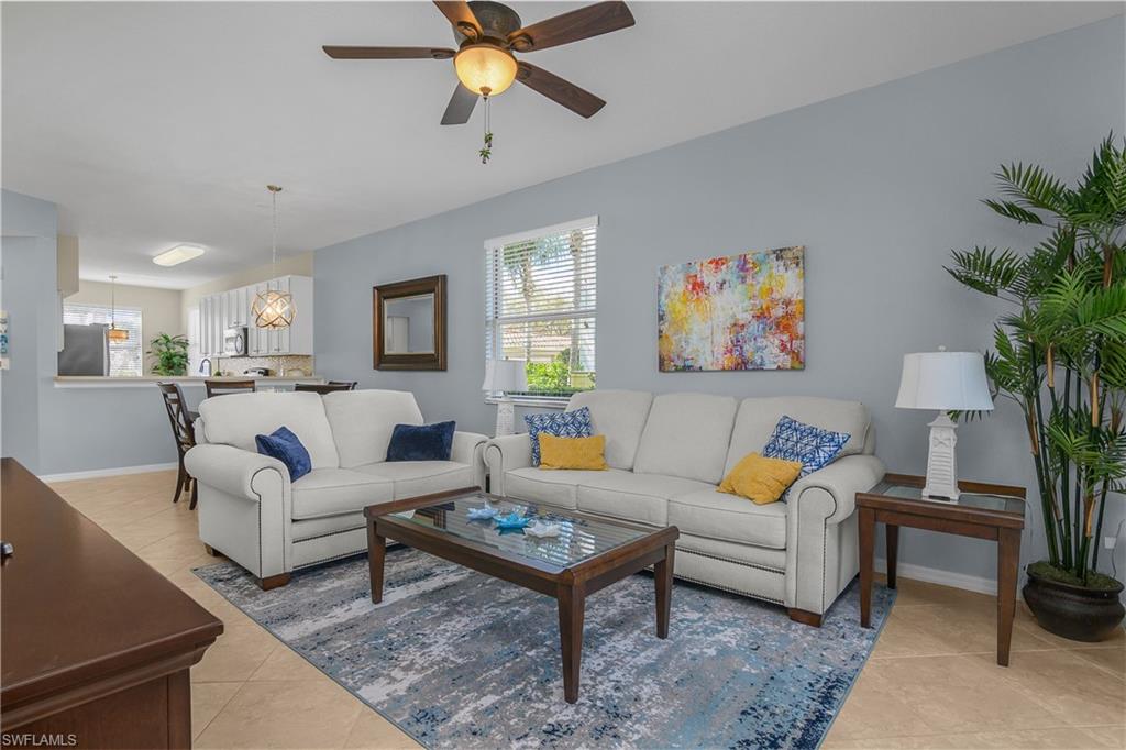Living room with white sofas, a glass-top coffee table, patterned rug, and colorful abstract wall art.