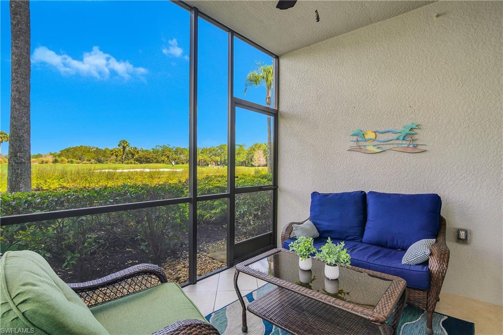 Screened lanai with blue and green seating and a view of open greenery.