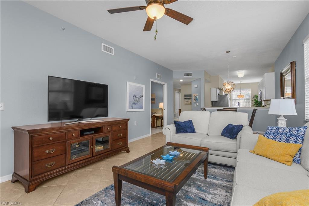 Living room with a white sectional, blue and yellow pillows, and a glass-top wooden coffee table.