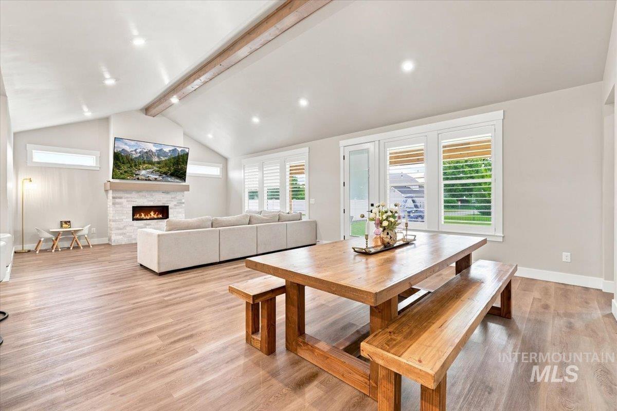 Open living and dining room with vaulted ceiling, stone fireplace, and large wooden farmhouse table.