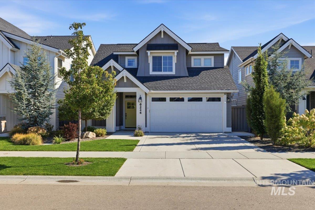 Gray two-story home with a double garage, front gable, and landscaped lawn.