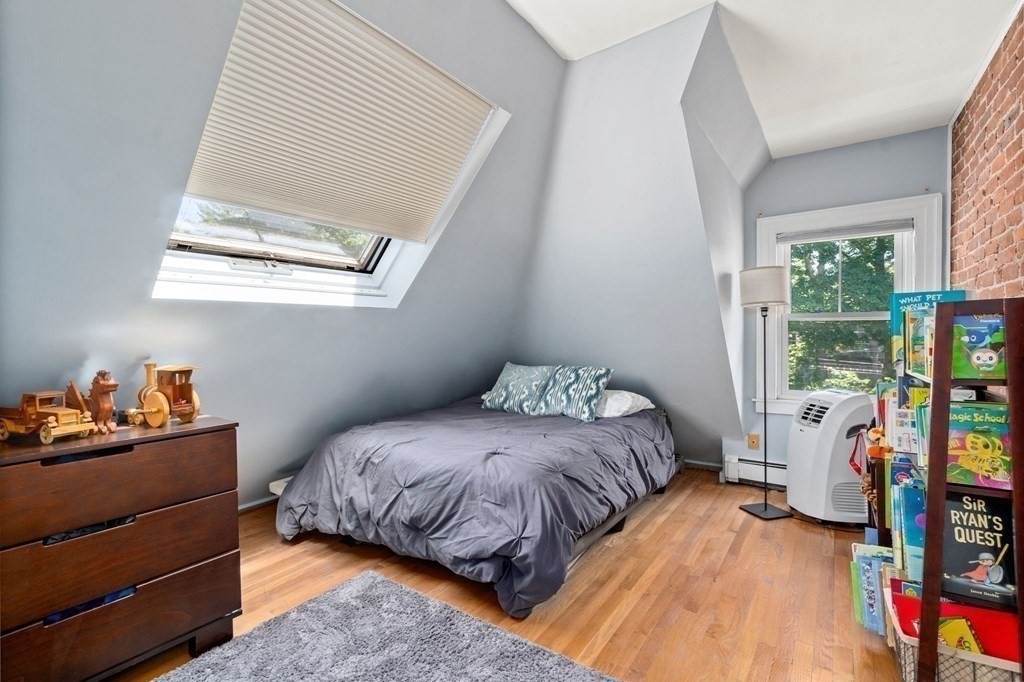 Attic bedroom with a skylight, sloped ceiling, exposed brick wall, and bed.