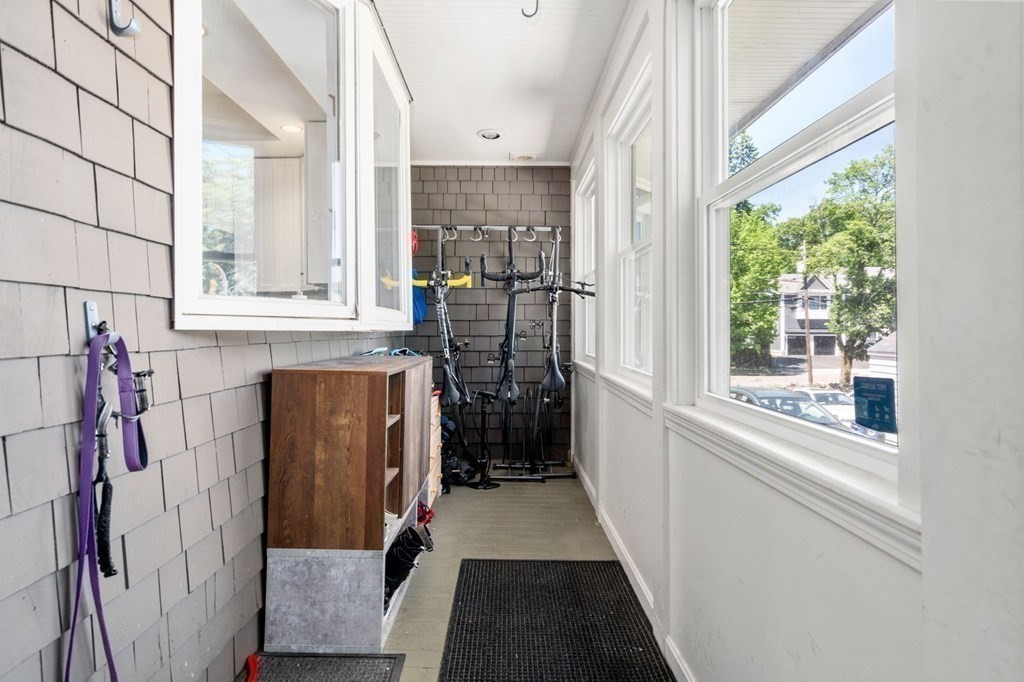 Enclosed porch with large windows, bicycle racks, and a wooden storage cabinet.