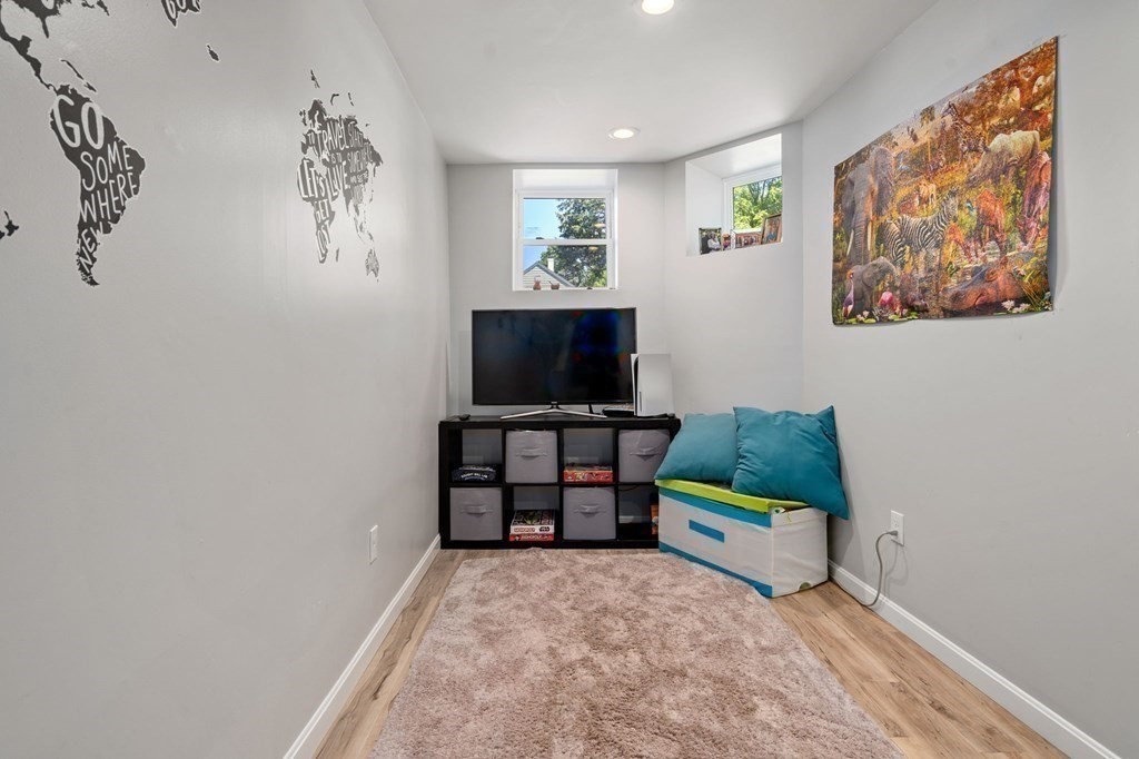 Furnished narrow room with a TV, teal cushions, a beige rug, and world map wall decals.