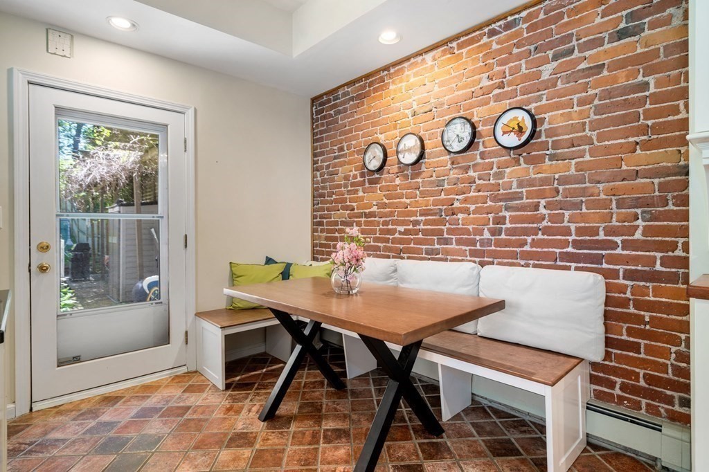 Dining nook with a wooden table, built-in bench seating, and exposed brick wall.