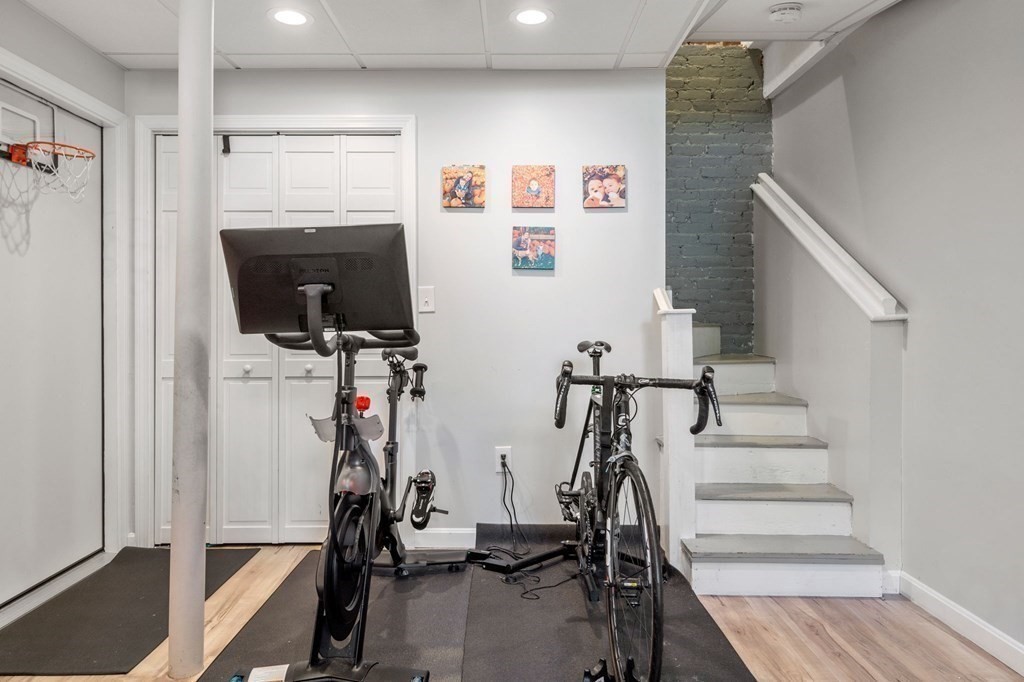 Exercise room with two bikes, built-in cabinets, a basketball hoop, and stairs.