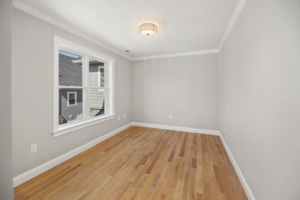 Empty room with warm hardwood floors and a large white-trimmed window.