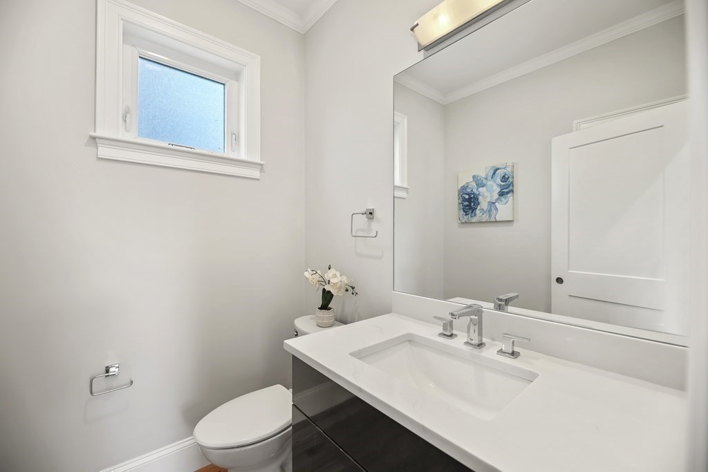 Bathroom with a white vanity, large mirror, and high frosted window.