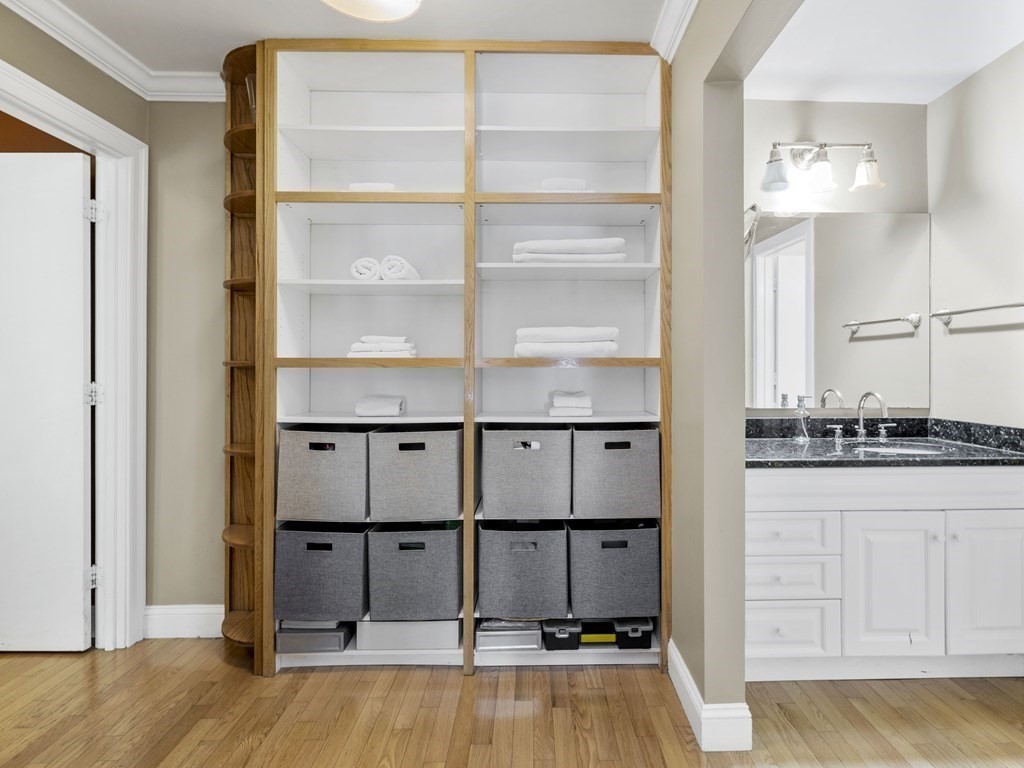 Bathroom with built-in wood shelving, towel storage bins, and a white vanity.