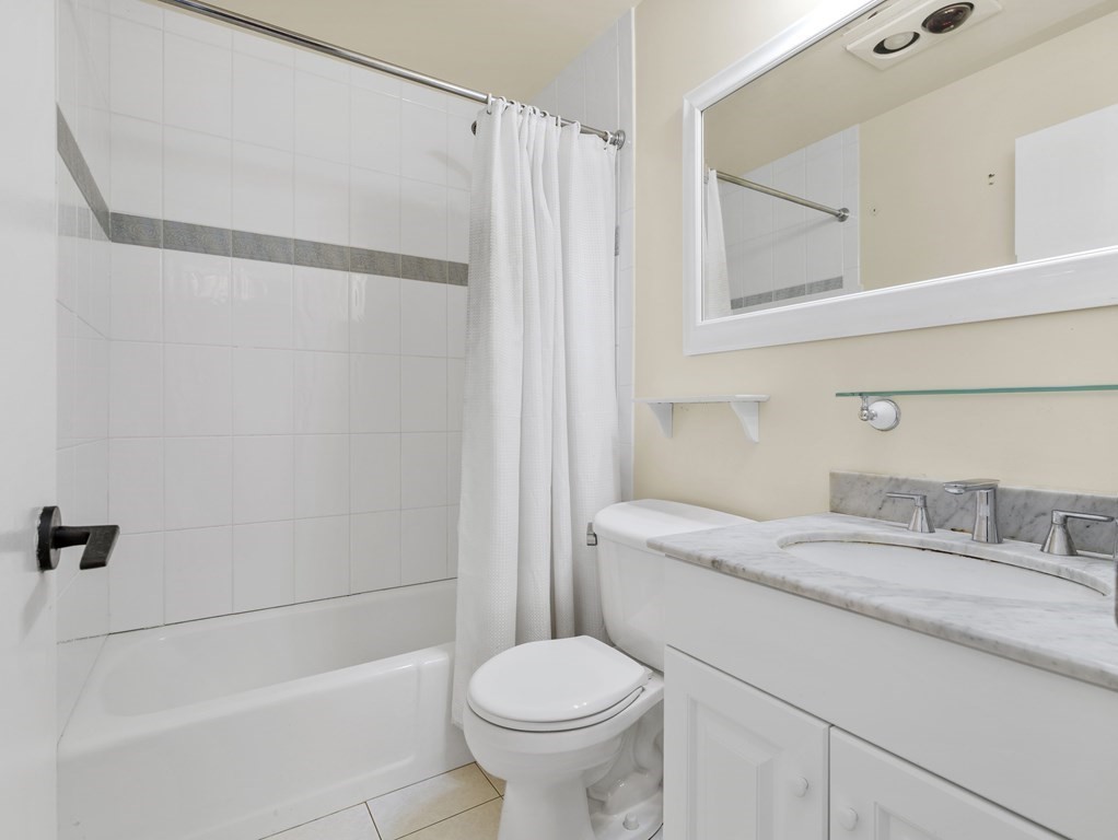 Bathroom with a tiled tub and shower beside a marble double-sink vanity.