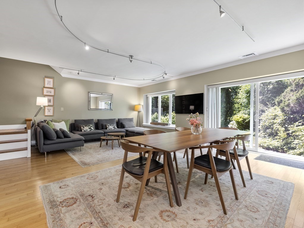 Open-plan living and dining room with a gray sectional and wood table beside sliding glass doors.