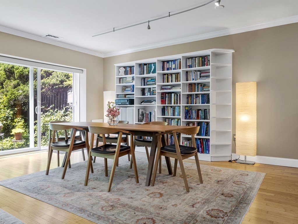 Dining room with a wooden table, book-filled shelves, and sliding glass doors to a garden.
