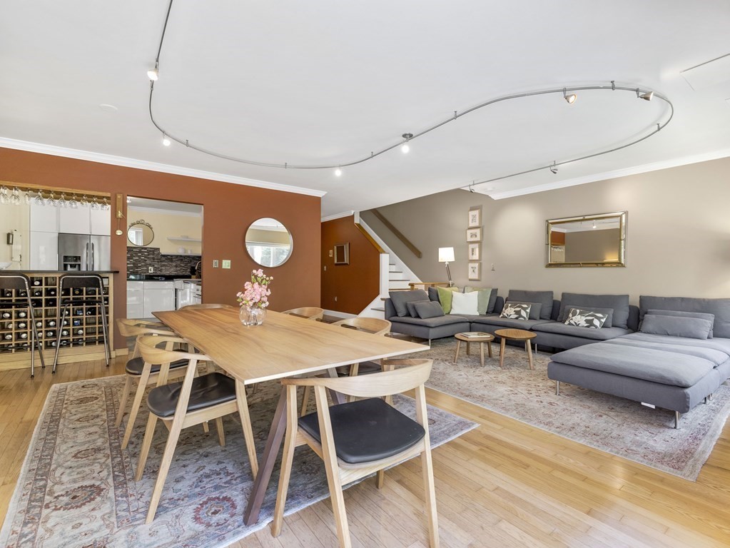 Open-plan living and dining room with a wood table, gray sectional, and kitchen breakfast bar.